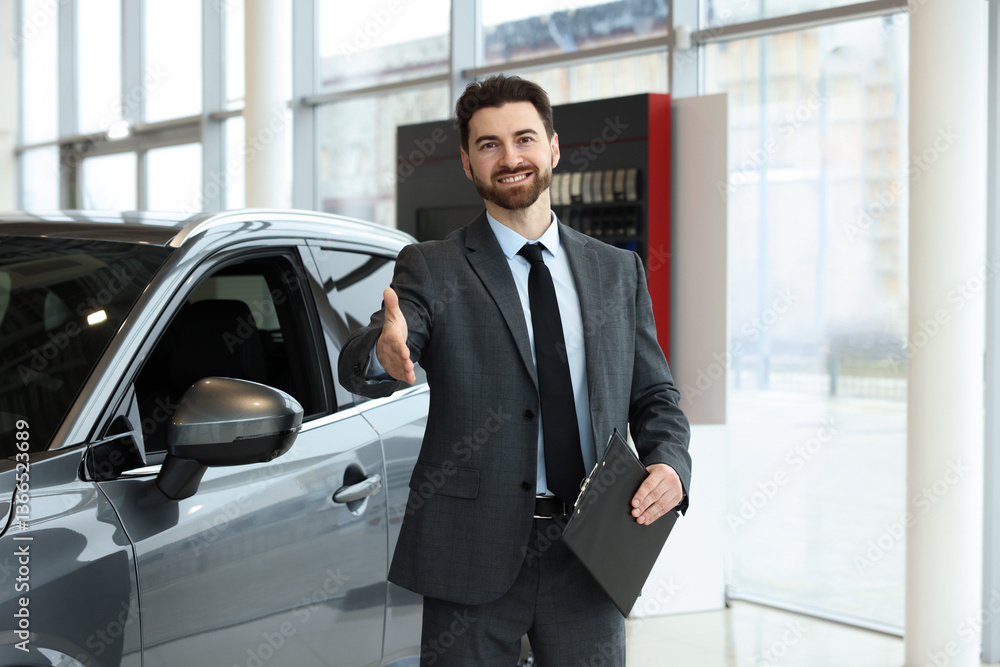 Happy salesman with clipboard offering handshake near new car in salon Happy salesman with clipboard offering handshake near new car in salon