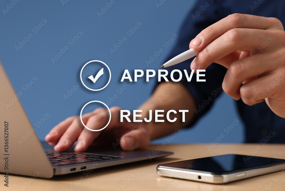 Approve or reject. Man using laptop at table against blue background, closeup