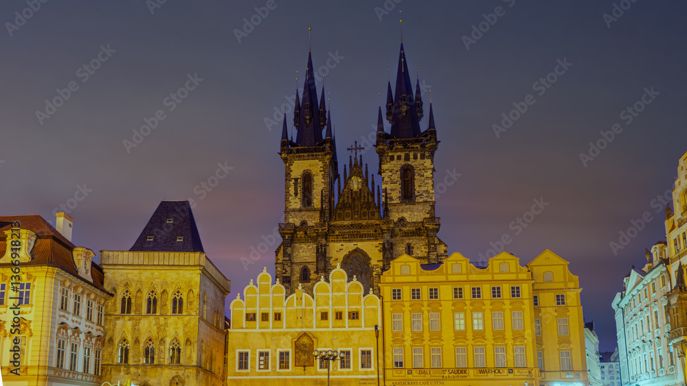 Fototapeta premium Prague, Czech Republic, at night features the iconic Prague Astronomical Clock tower, brightly lit and dominating the Old Town Square, with a deep blue sky providing a dramatic backdrop.