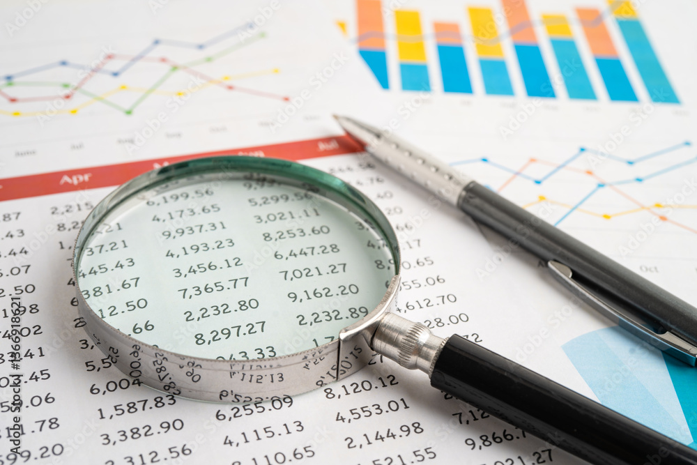 Magnifying glass on spreadsheet and graph paper. Financial data economy, Business. Magnifying glass on spreadsheet and graph paper. Financial data economy, Business.