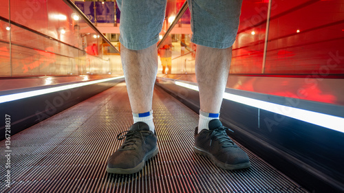 A man stands safely on a moving walkway or escalator, with proper positioning—feet placed firmly and centered—demonstrating essential safety practices to maintain balance and avoid potential accidents
