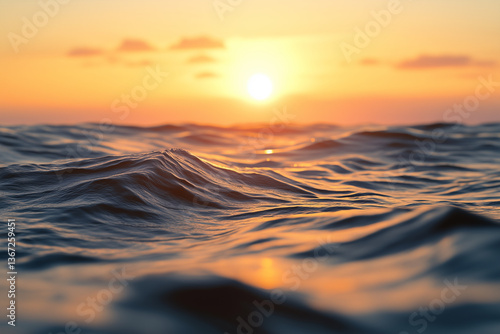 A vast ocean with gentle waves rolling across the surface, reflecting the golden light of a setting sun. The perspective is close to the water level, capturing the rich texture of the waves.
