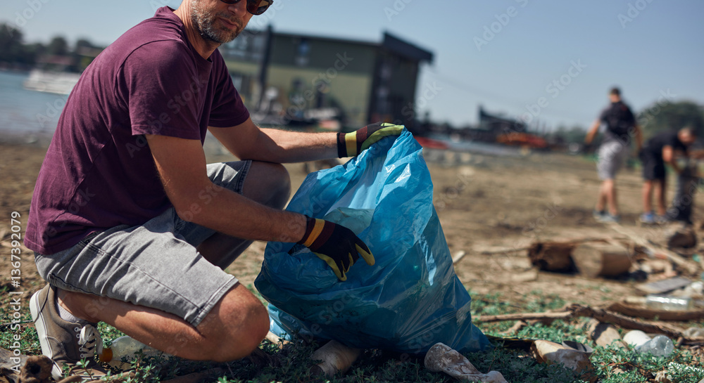 Environmental activist cleaning river shore from piled up trash.