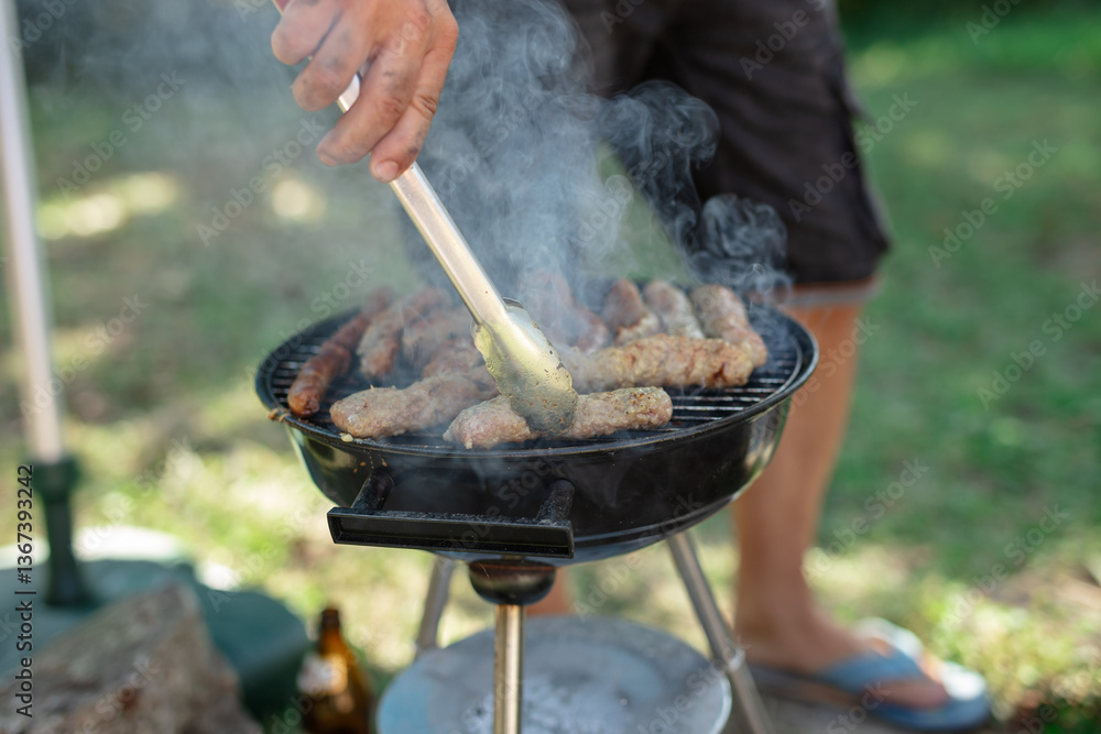 Man preparing barbeque in the garden on a hot summer day.
