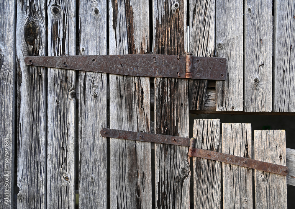 Rustic wooden door with metal hinges shows weathered texture and historical charm in a countryside setting