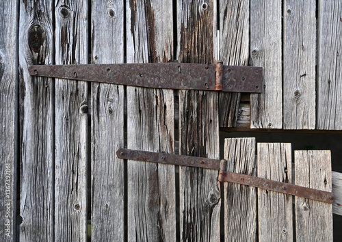 Obraz na płótnie Rustic wooden door with metal hinges shows weathered texture and historical charm in a countryside setting w salonie