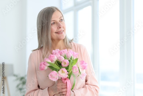 Smiling woman with bouquet of tulips at home. Space for text