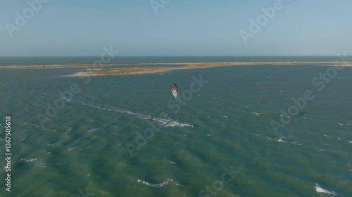 Kitesurfer glides on turquoise lagoon at Ilha do Guajiru, Ceará, Brazil, on windy day
