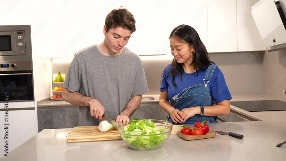 Multiethnic couple working together while creating nutritious salad, chopping fresh vegetables on kitchen countertop with shared culinary passion and teamwork Multiethnic couple working together while creating nutritious salad, chopping fresh vegetables on kitchen countertop with shared culinary passion and teamwork