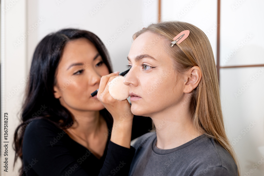 Professional makeup artist carefully applying eyeshadow to a young woman in a beauty salon. The setting is bright and modern, showcasing a beauty treatment in progress. Professional makeup artist carefully applying eyeshadow to a young woman in a beauty salon. The setting is bright and modern, showcasing a beauty treatment in progress.