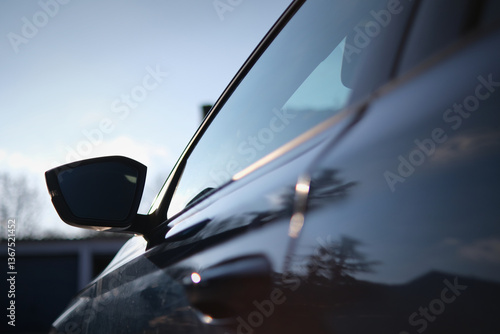 Φωτογραφία Close-up of a car’s side mirror and door with glossy reflections of the sky and trees, showcasing a sleek design, smooth curves, and tinted windows