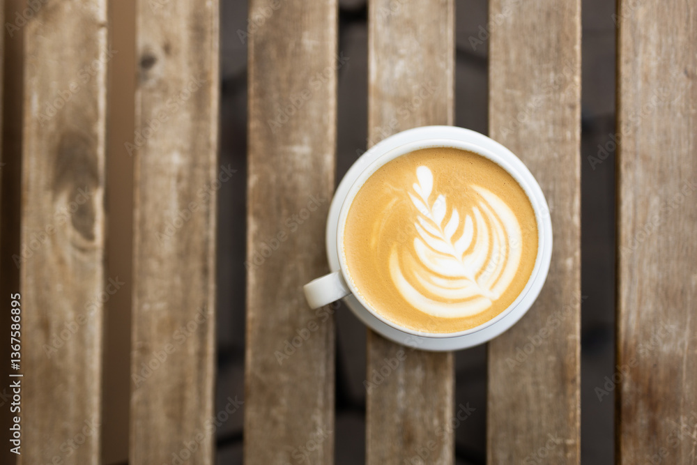 Cup of coffee on the wooden table with latte art. Street coffee, top view. Coffee in a white cup with latte art.