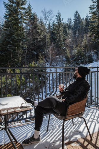 Man Enjoying Coffee on a Snowy Balcony