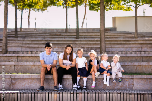 Group of Children and Teens Sitting on Bench in Outdoor Amphitheater