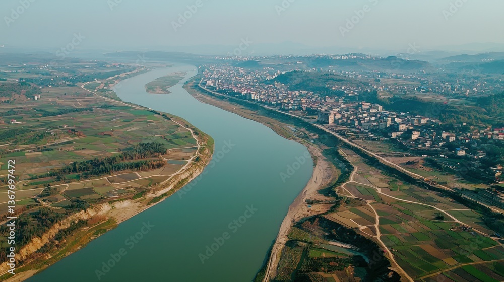 Obraz premium Aerial View of a Serene River Meandering Through Lush Farmlands and a Small Town