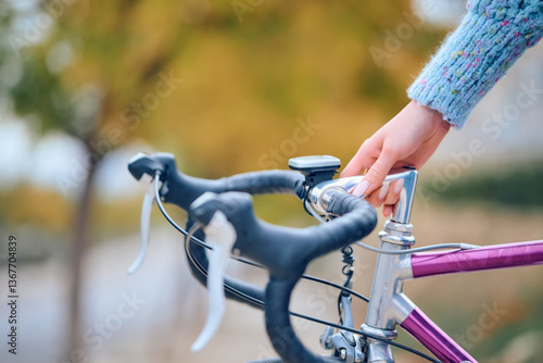 Fotografie Person adjusting bicycle handlebar on a sunny autumn day in a park