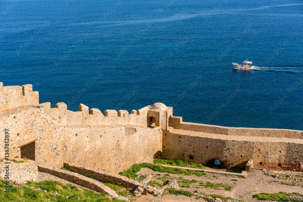 Monemvasia island historic city stone wall with a boat on the sea, Monemvasia, Laconia Monemvasia island historic city stone wall with a boat on the sea, Monemvasia, Laconia