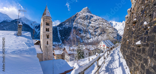 View of snow covered mountains, rooftops and Church of Saint Pantalon in Courmayeur in winter, Courmayeur, Aosta Valley, Italian Alps