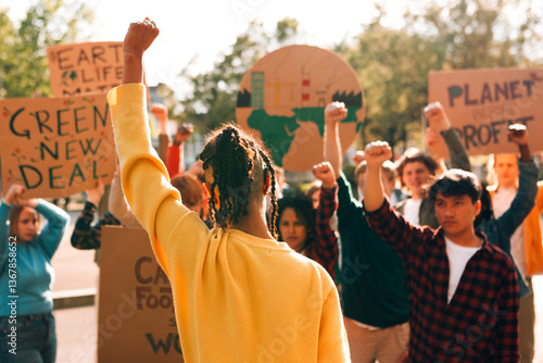 Group of activists protesting for climate action, raising fists and holding signs for environmental justice