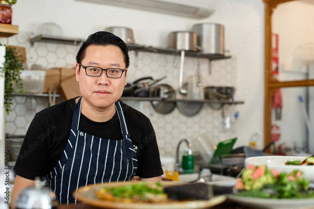 Asian chef working in kitchen at organic food cafe Asian chef working in kitchen at organic food cafe
