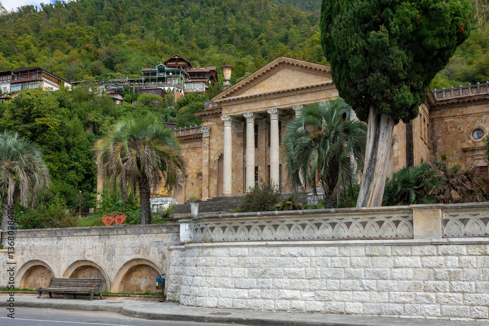 Fototapeta premium Gagra, Abkhazia-October 11 2024 : Old historical building with columns among the mountains in the Republic of Abkhazia. Building of the Winter Theater in Gagra. Sunny autumn day