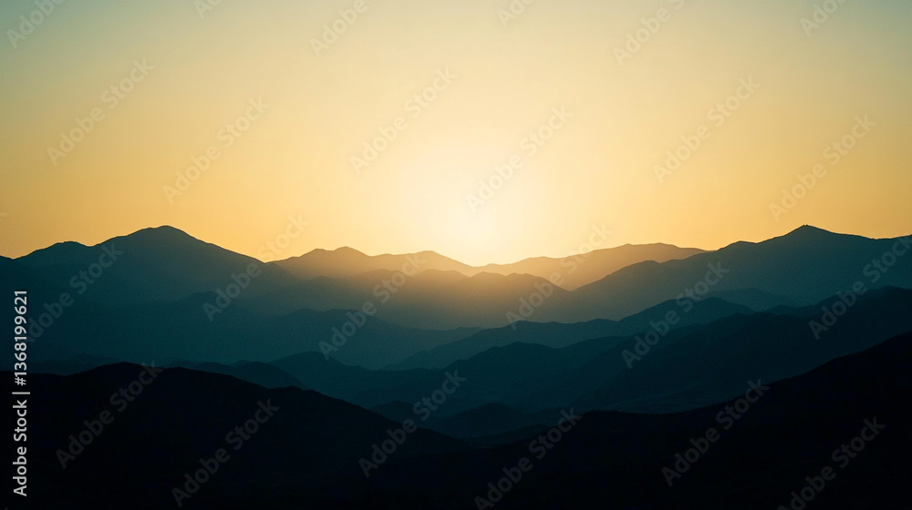 Fototapeta premium A scenic view of layered mountains under a warm sunset sky with soft light and distant peaks