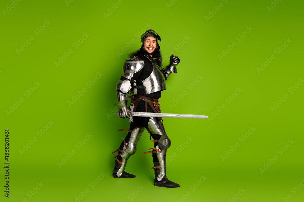 Young man in medieval knight armor with sword posing on a bright green background Young man in medieval knight armor with sword posing on a bright green background
