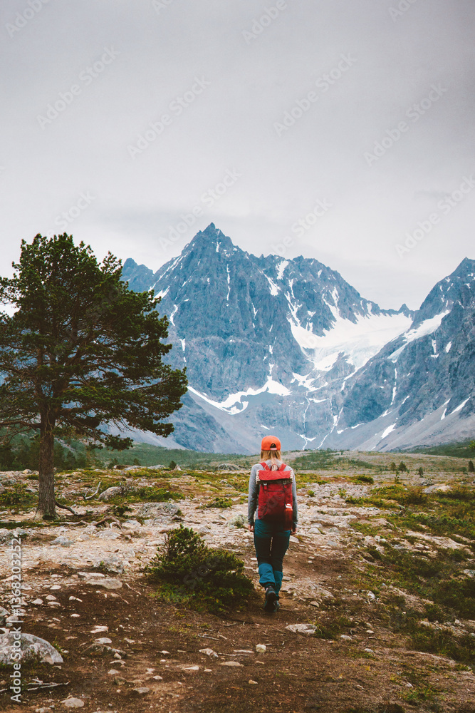 Fototapeta premium Woman climbing mountains in Norway travel solo active summer vacations adventure lifestyle trip, tourist roams solo with backpack eco tourism in the wild