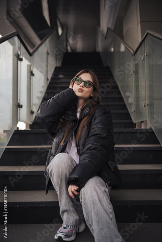 Stylish young woman in a black jacket on a city street on a cool day