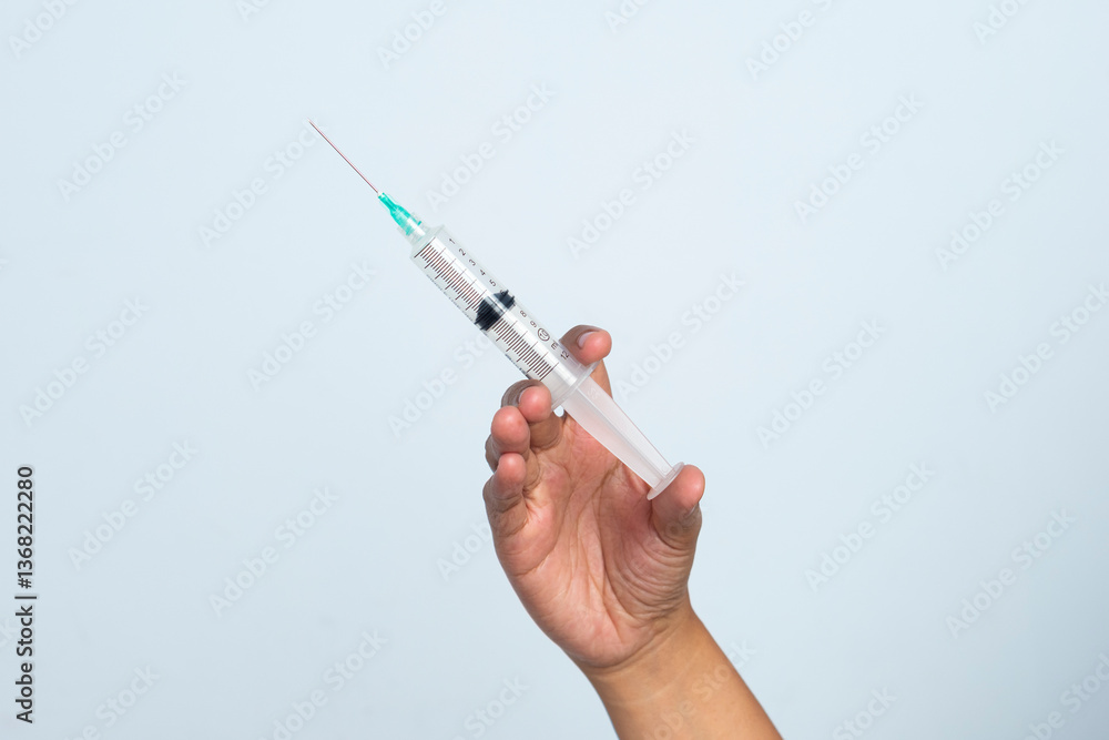 Asian woman's hand holding an injection on a white background. The hand holds a syringe. Asian woman's hand holding an injection on a white background. The hand holds a syringe.