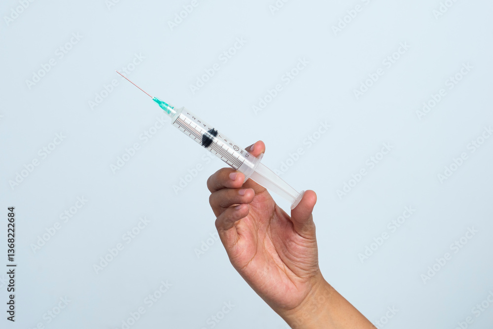 Asian woman's hand holding an injection on a white background. The hand holds a syringe. Asian woman's hand holding an injection on a white background. The hand holds a syringe.