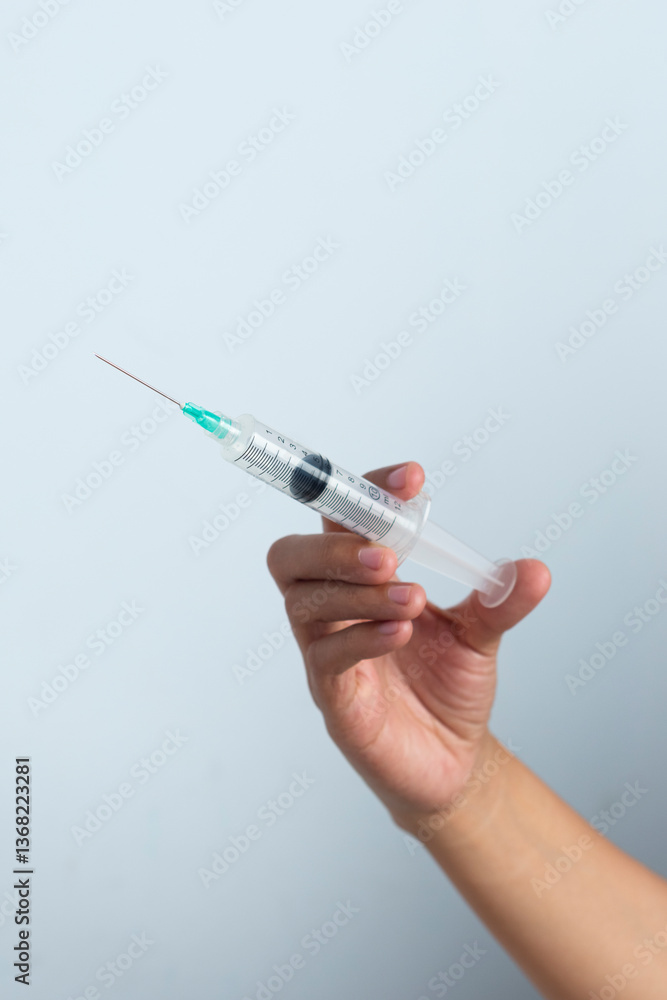 Asian woman's hand holding an injection on a white background. The hand holds a syringe. Asian woman's hand holding an injection on a white background. The hand holds a syringe.