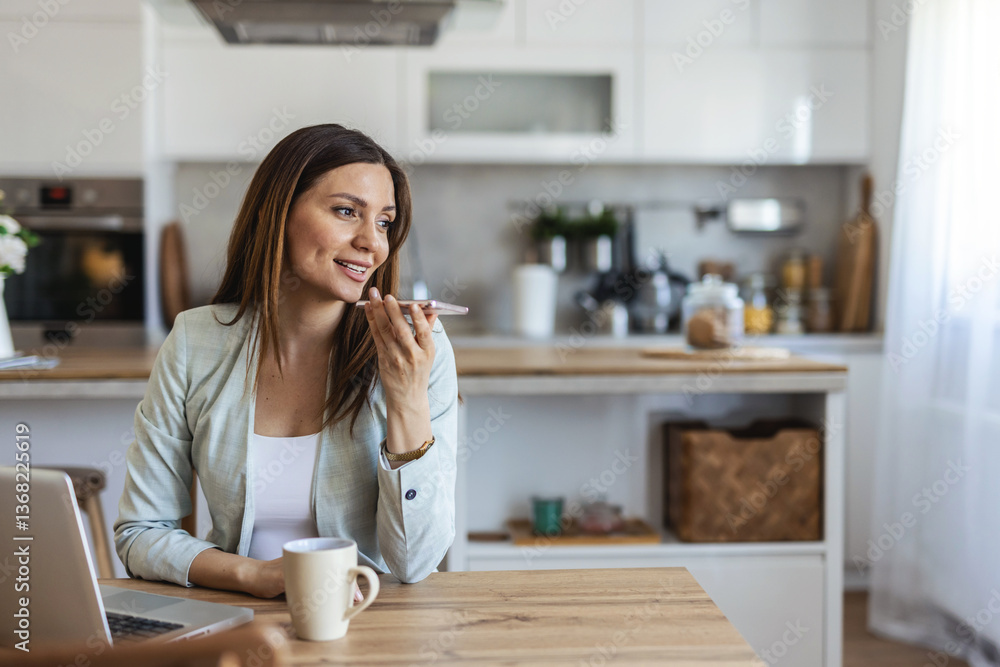 A business woman setting at home, communicates using her smartphone while working on a laptop, reflecting modern remote work culture. A business woman setting at home, communicates using her smartphone while working on a laptop, reflecting modern remote work culture.