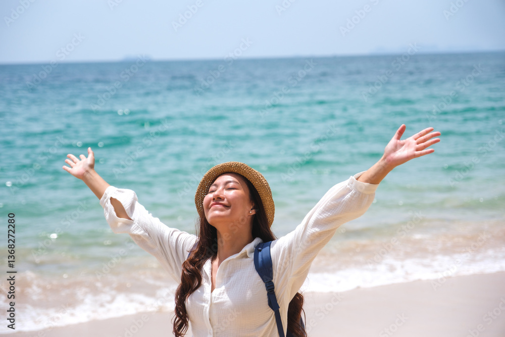 Portrait of a young woman with hat and backpack open arms by the sea Portrait of a young woman with hat and backpack open arms by the sea