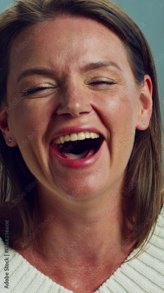 Woman smiles joyfully while expressing happiness in slow motion. Sitting in a living room, she showcases a cheerful demeanor against a softly blurred background Woman smiles joyfully while expressing happiness in slow motion. Sitting in a living room, she showcases a cheerful demeanor against a softly blurred background
