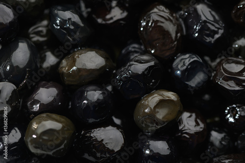 Delicate glimmer of shiny black olives nestled together in a bowl, showcasing a harvest's bounty from sun-drenched orchards