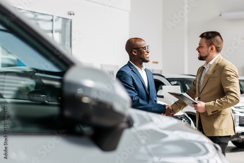 Tableau sur toile An auto dealer closes a deal or a successful consultation with a handshake with an African-American customer