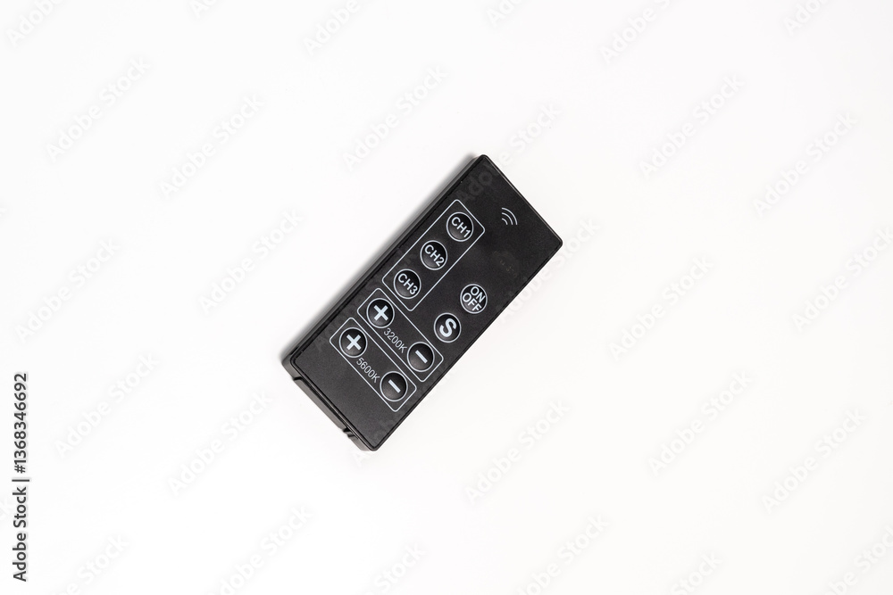 A black electronic remote control with various buttons, including channel and temperature adjustments. Isolated on a white background. A black electronic remote control with various buttons, including channel and temperature adjustments. Isolated on a white background.