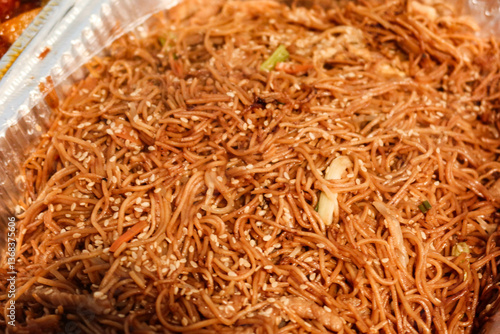 close up of Chinese stir fried noodles in an aluminium foil tray