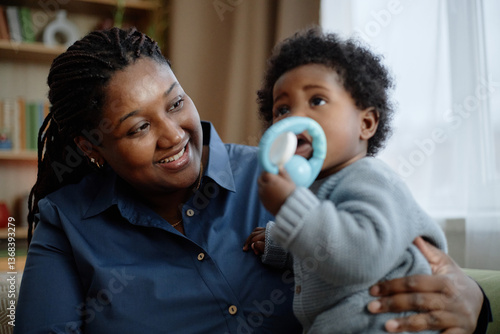 Photography Portrait of joyful Black mother gently embracing little daughter looking at chil