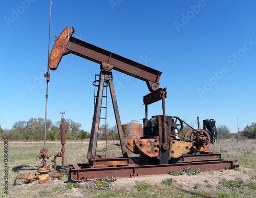 Canvas Print Idle, rusty oil well pump jack abandoned in field in West Texas.