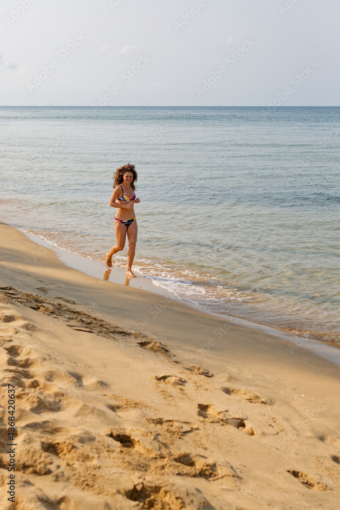 Joyful woman in bikini runs along sandy shore at morning, hair blowing in wind. Carefree summer travel mood, tropical getaway happiness. Joyful woman in bikini runs along sandy shore at morning, hair blowing in wind. Carefree summer travel mood, tropical getaway happiness.