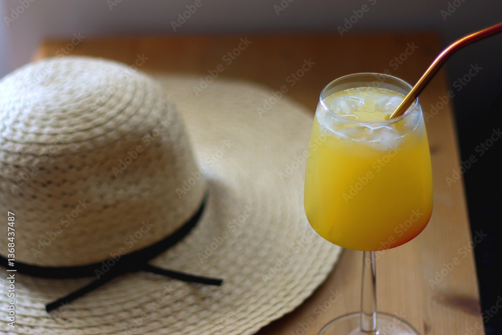 Plate with watermelon slices, glass of orange juice or cocktail, straw hat, colorful beaded necklace and sunglasses on the wooden table. Summer essentials concept. Selective focus.
