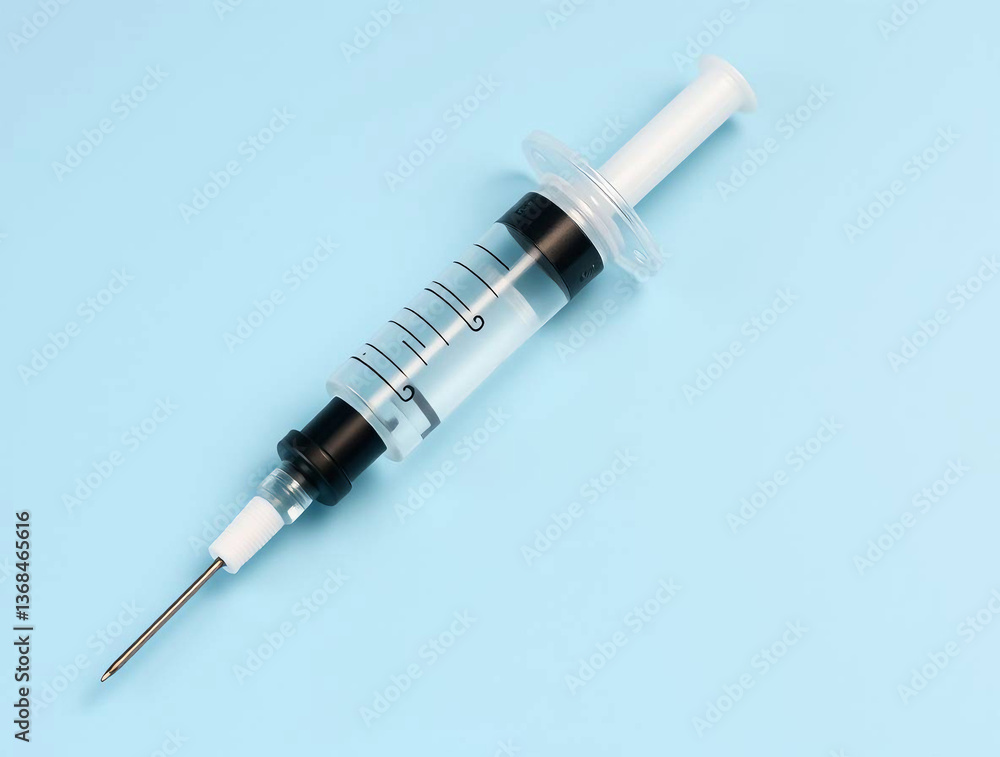 single syringe placed diagonally on a solid light blue background single syringe placed diagonally on a solid light blue background