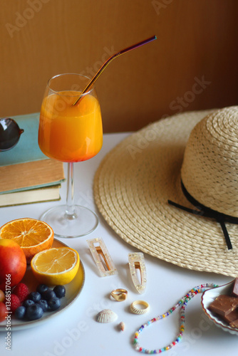 Obraz na płótnie Glass of cocktail, straw hat, sunglasses, books, fresh fruit, chocolate and accessories. Summer essentials on the table. Selective focus. w salonie