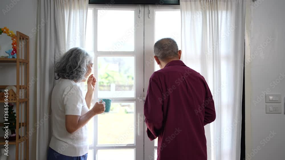 Elderly couple standing together by bright window, enjoying peaceful moment while drinking and sipping drinks at home. Elderly couple standing together by bright window, enjoying peaceful moment while drinking and sipping drinks at home.