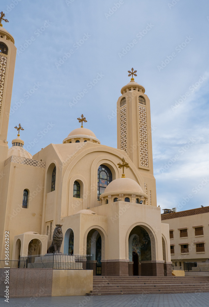 Exterior view of El Sama Ayen Coptic Orthodox Church in Sharm El Sheikh. Modern religious building with decorative crosses against the background of steel gates