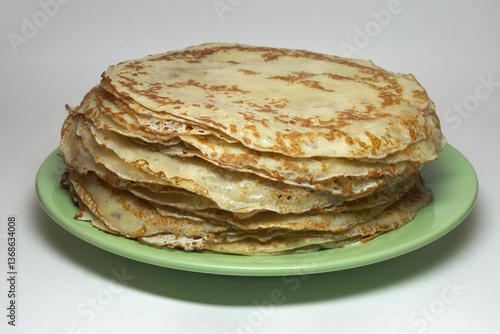 blynchyky stacked on green plate, traditional for Crepe week festive. round thin dough products, on milk and eggs. fried on pan