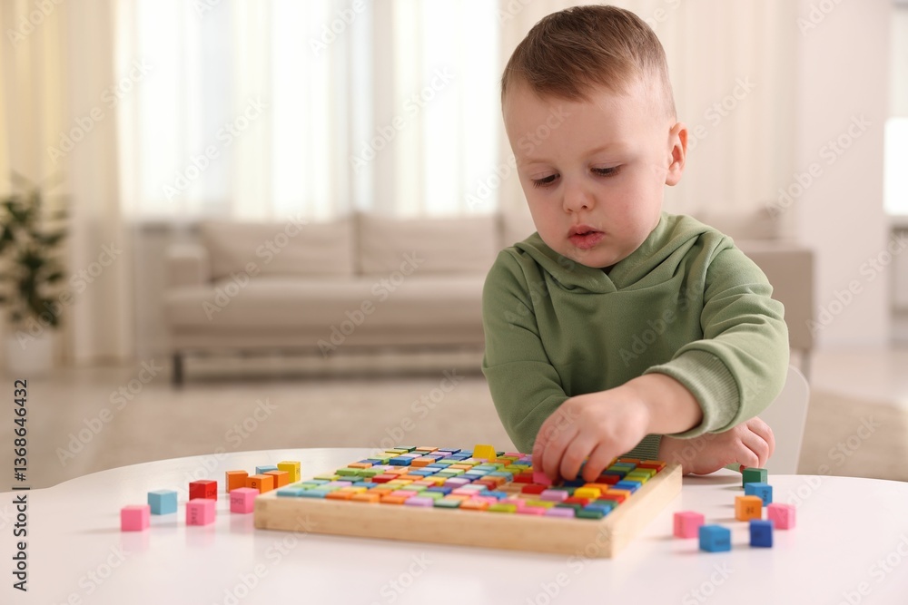 Motor skills development. Little boy playing with Times table tray indoors Motor skills development. Little boy playing with Times table tray indoors