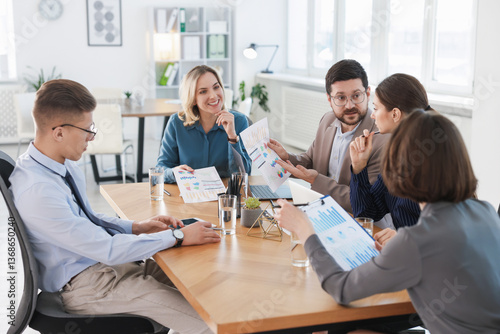 Coworkers working together at wooden table in office
